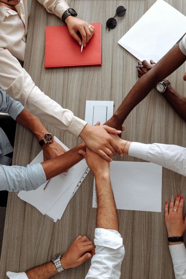 Mehrere Personen legen bei einem Teamtag ihre Hände übereinander und symbolisieren Zusammenarbeit, Vertrauen und Zusammenhalt.